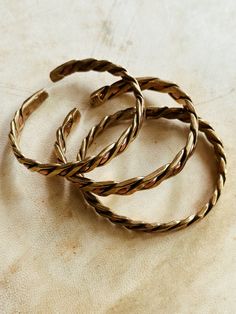 three gold bracelets sitting on top of a table