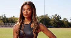 a beautiful young woman standing in front of a soccer field with her hands on her hips