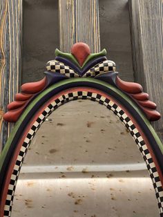 an ornate mirror is hanging on the side of a wooden wall with a checkerboard design