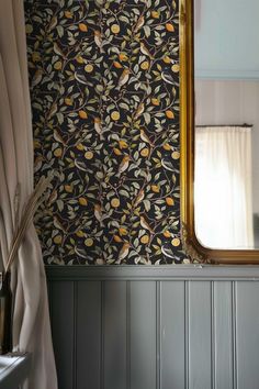 a mirror sitting on top of a wooden table next to a wall covered in birds