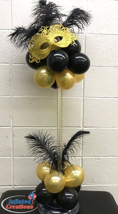 some black and gold balloons are hanging from a pole with masks on it, along with other decorations