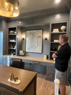 a man standing in front of a desk with a map on the wall behind him