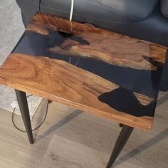 a wooden table sitting on top of a hard wood floor next to a black leather chair