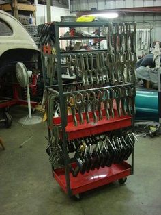 there is a red cart with many tools on it in the garage and some cars