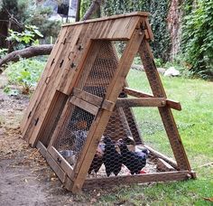 an outdoor chicken coop made out of wood with chickens in it and one on the ground