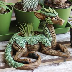 there is a statue of a dragon sitting in front of potted cacti