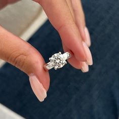 a woman's hand holding an engagement ring