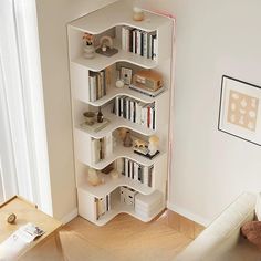 a white book shelf filled with books in a living room next to a couch and window