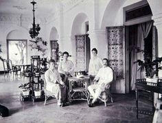 black and white photograph of four men sitting at a table in a room with ornately decorated walls