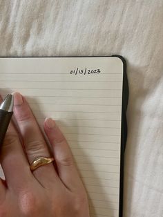 a woman's hand holding a pen and writing on a notepad