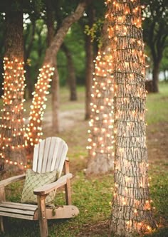 a white chair sitting next to a tree covered in lights