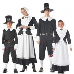 three adults and two children dressed in black and white clothing, one is wearing a top hat