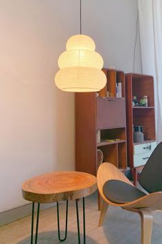 a living room with two chairs and a table in the middle, next to a bookshelf