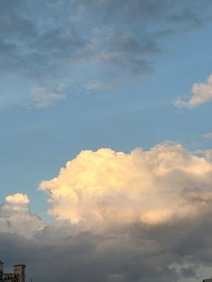 an airplane is flying high in the sky above some buildings with clouds and blue sky behind it