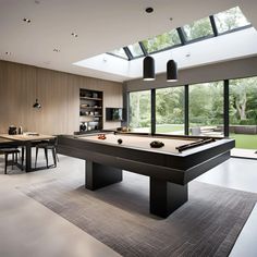 a pool table in the middle of a room with large windows and lots of furniture