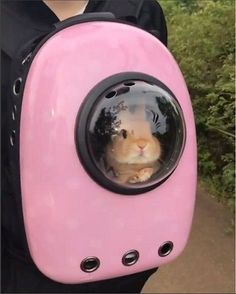 a person holding a pink backpack with a small animal in it