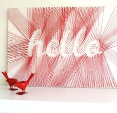 two red birds standing in front of a white wall with the word hello written on it