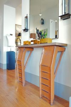 a wooden table sitting on top of a hard wood floor next to a mirror and lamp