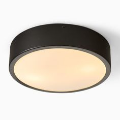 a black circular light fixture on a white wall