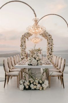 a table with white flowers on it and chandelier hanging from the ceiling above