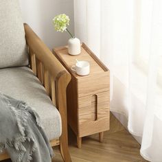 a small wooden table with a vase on it next to a chair and a window