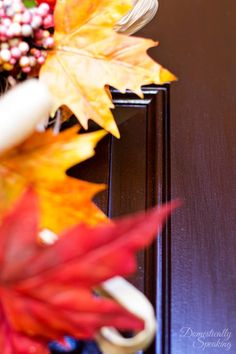 an arrangement of fall leaves and other decorations on a wooden table in front of a door