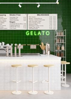 a green tiled restaurant with three stools in front of the counter and two menu boards on the wall