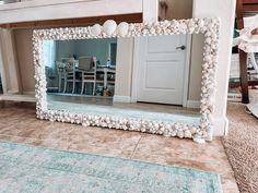 a large mirror sitting on top of a floor next to a rug and table with chairs