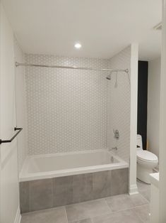 a white bathroom with tile flooring and walls