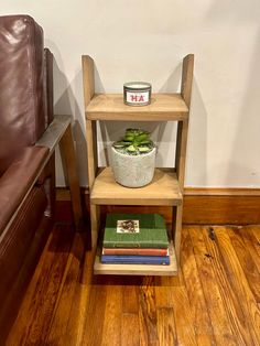 a wooden shelf with a potted plant on it next to a brown leather chair