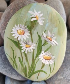 a painted rock with white daisies on it