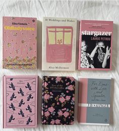 four books are lined up on a bed sheet, one is pink and the other is blue