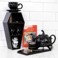 a black tea pot sitting on top of a counter next to a shelf filled with books