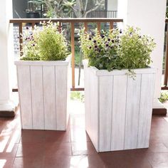 two white planters sitting on top of a tiled floor