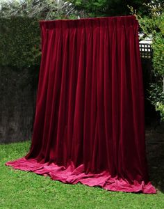 a red curtain sitting on top of a lush green field