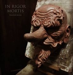 a sculpture of an old man's head on top of a piece of wood