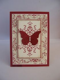 a red and white card with a butterfly on the front, in an ornate frame