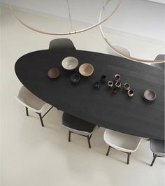 a black table with white chairs around it and some bowls on the table next to it