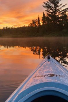 a kayak is sitting on the water at sunset