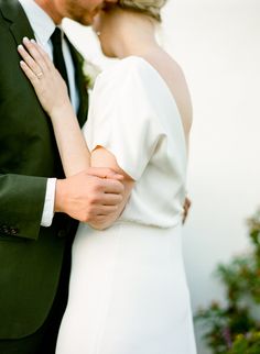 a bride and groom kissing each other outside