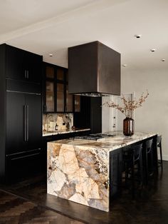 a large kitchen with black cabinets and marble counter tops on the island in the middle of the room