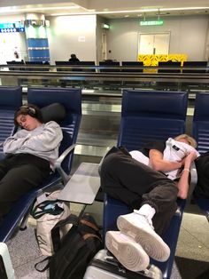 two people sleeping on blue chairs in an airport with their heads resting on each other