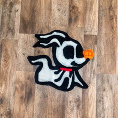 a black and white dog rug with an orange ball in its mouth on the floor