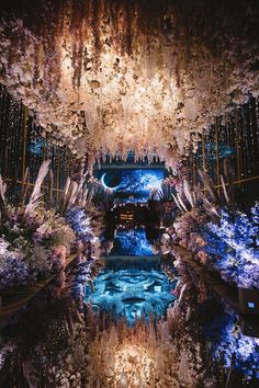 the inside of a building with lights and flowers on it's walls, reflecting in water