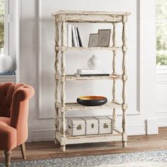 a white bookcase with books and a bowl on it next to a chair in a living room