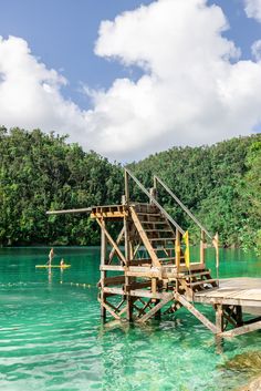 a wooden dock sitting on top of a body of water next to a lush green forest