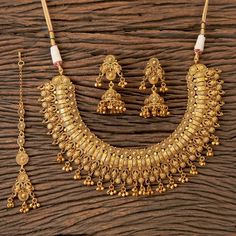 a gold necklace and earring set on a wooden surface, with beads hanging from it