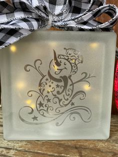 a glass block with a christmas tree on it and lights in the shape of a bird