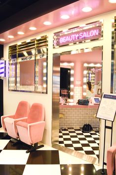 two pink chairs sitting in front of a beauty salon with black and white checkered floor