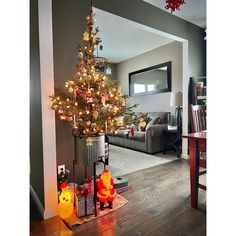 a decorated christmas tree in the middle of a living room with other decorations on the floor